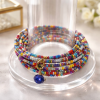 This delightful 10 layer bracelet is made with memory wire and rainbow confetti seed beads with a blue round crystal dangle.